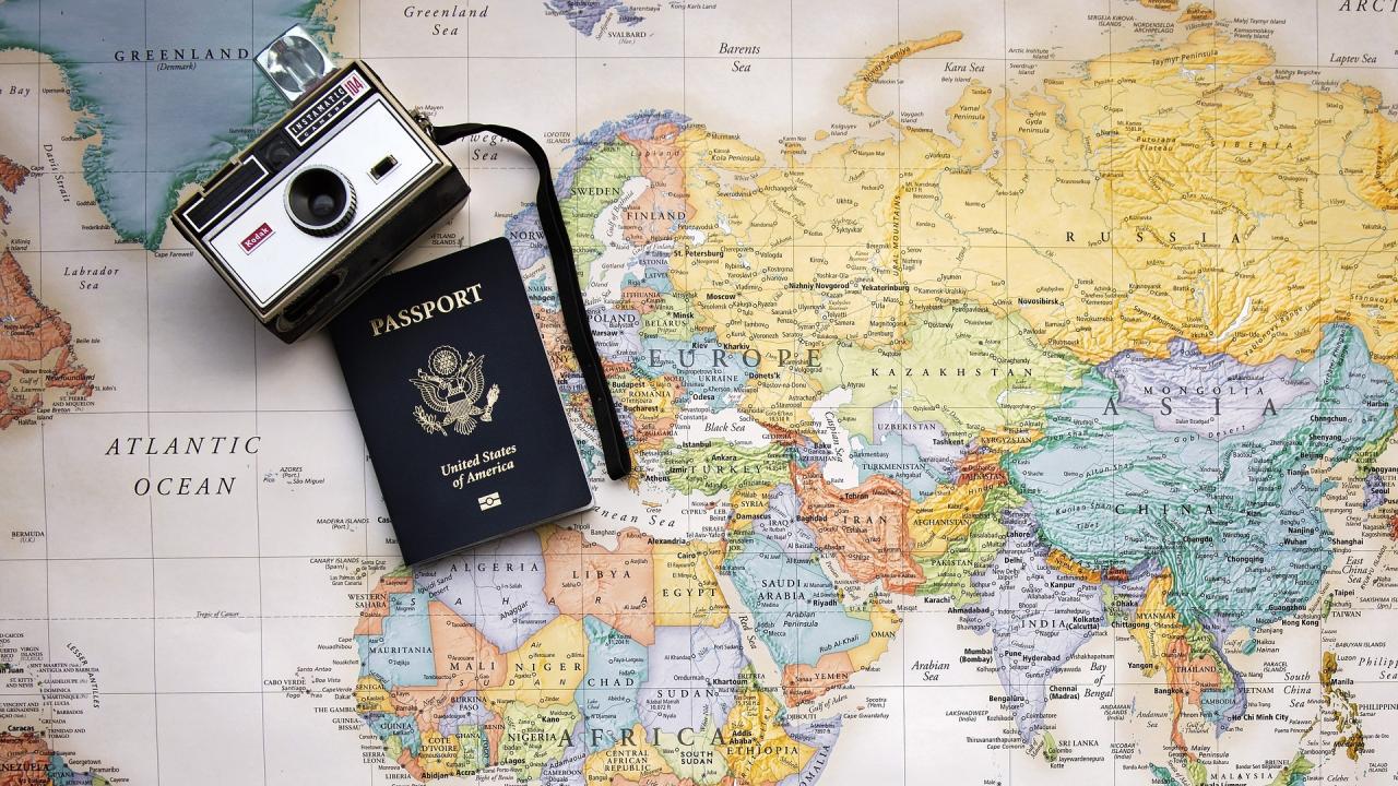 Photo of a map with a passport and camera in the upper left corning.